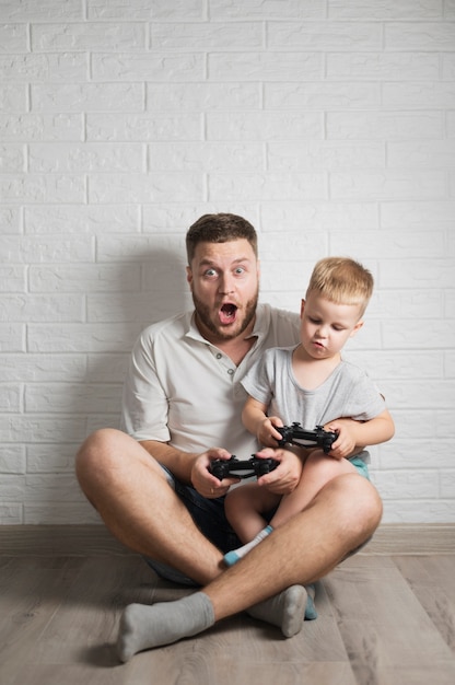Возбужденный отец и сын играют в игры дома