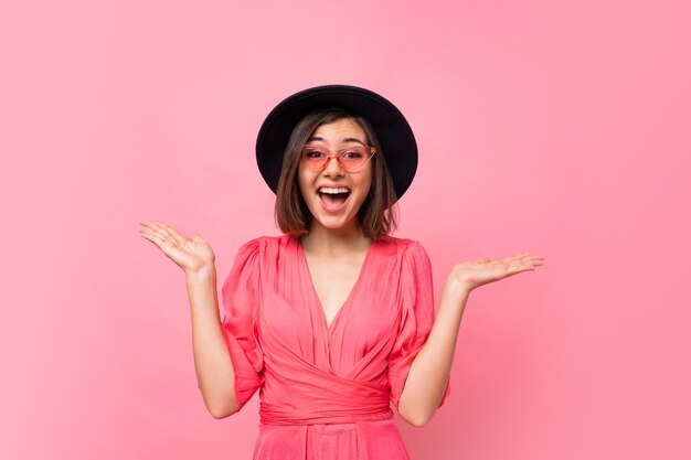 Exited laughing woman in stylish hat posing on pink wall