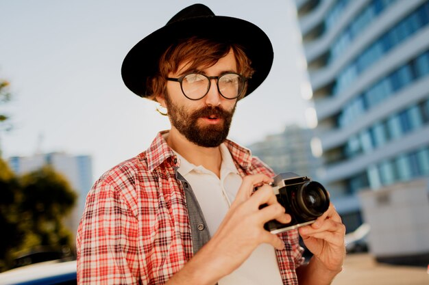 Exited man with beard with interesting using retro film camera , making photos