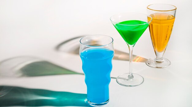 Exotic cocktail in different type of glasses with shadow on white backdrop