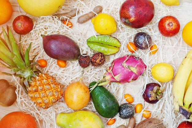 Exotic fruits on wooden background Healthy eating dieting food Pitahaya carambola papaya baby pineapple mango passion fruit tamarind and other