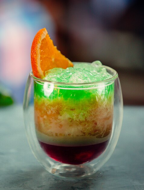 exotic juice with green ice shaving with orange slice on top