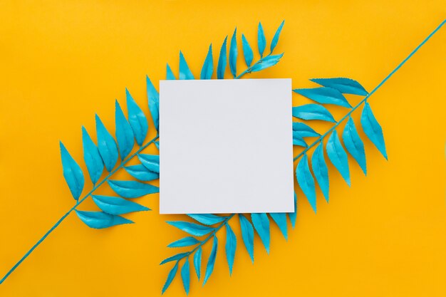 Exotic tropical leaves and blank paper on yellow