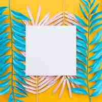 Free photo exotic tropical leaves and blank paper on yellow