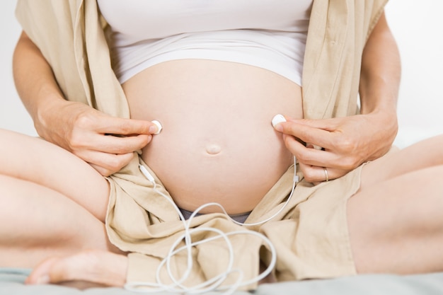 Free photo expectant mother making her baby listening to music