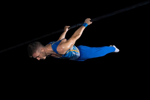 Experience. Muscular male gymnast training in gym, flexible and active