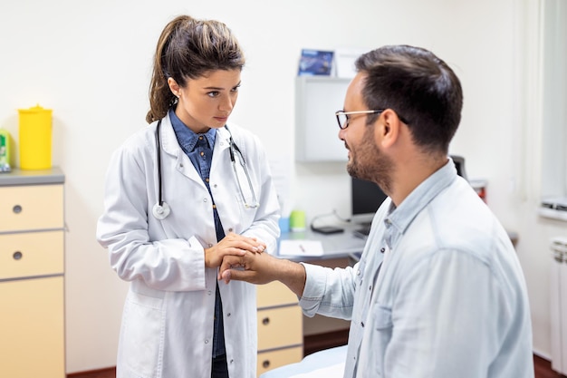 Free photo experienced doctor discussing with patient his private medical file young man checking up with his md and consulting about the way of his health treatment and health insurance