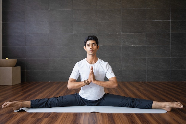 Foto gratuita yogi indiano con esperienza che fa le spaccature in palestra