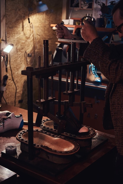 Free photo experienced man is using a press tool at his new workshop.