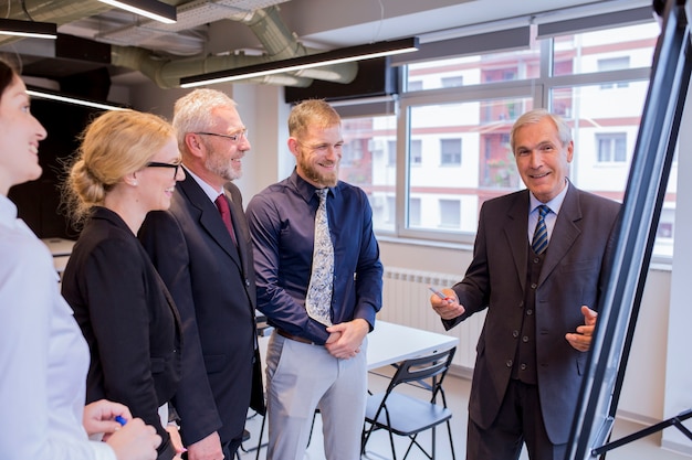 Experienced smiling businessman giving presentation to executive team