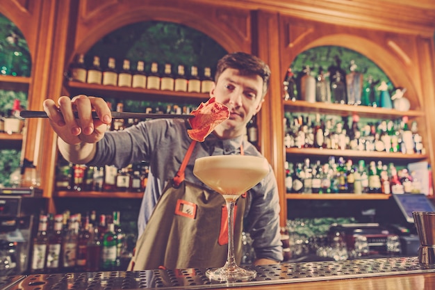 Expert barman is making cocktail at night club or bar.