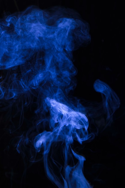 Explosion of blue smoke against black background