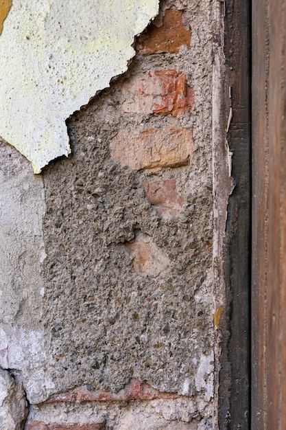 Открытая кирпичная стена с облупленной бетонной поверхностью
