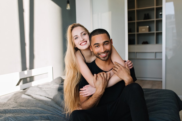 Expressing true lovely emotions, joy of young couple hugging on bed in sunny morning in modern apartment. Relationship, in love, leisure, smiling, at home, relax, happiness