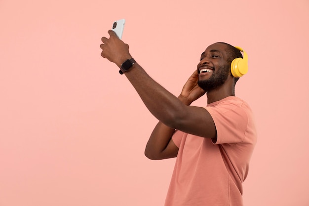 Foto gratuita uomo afroamericano espressivo che ascolta la musica sulle cuffie