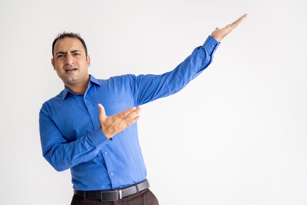 Expressive Indian man pointing aside with both hands