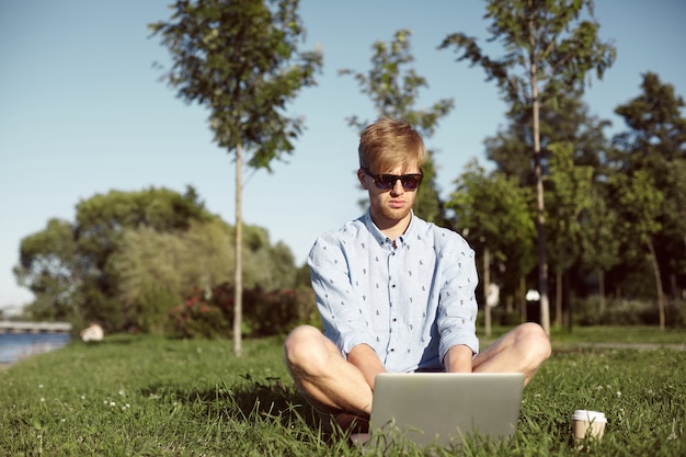 Expressive man is in the park with his laptop