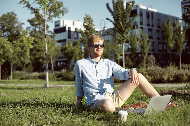 Expressive man is in the park with his laptop