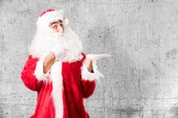 Expressive santa claus pointing at his left hand