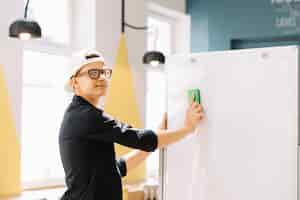 Free photo expressive schoolboy cleaning blackboard