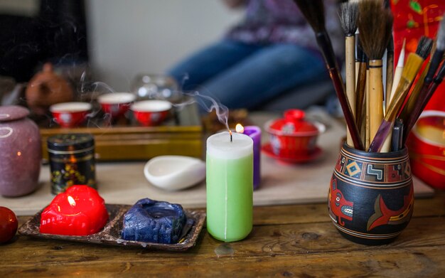 Extinguished candle with smoke in front of tea set on wooden table
