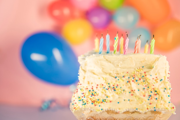 Extinguishing candles on cake with blurred balloons