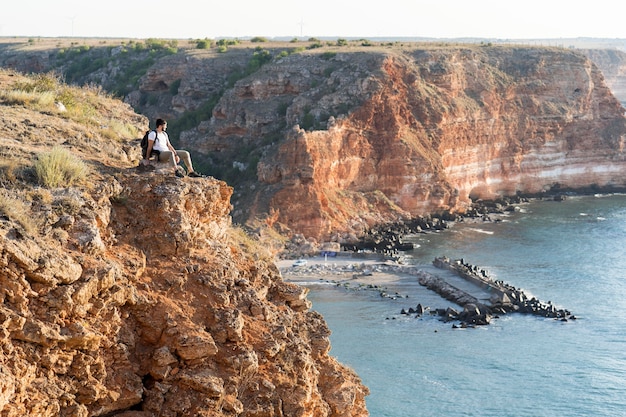 Foto gratuita uomo di tiro extra lungo seduto su una costa con spazio di copia