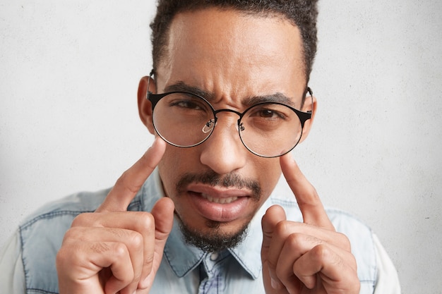 Free photo extreme close up of mixed race serious afro american guy with mustach and beard keeps fore finger in front