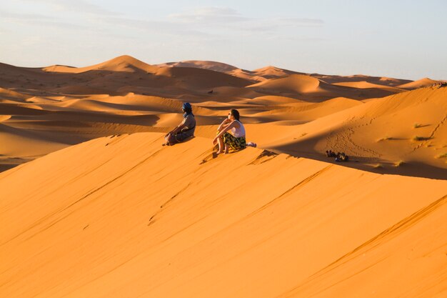 Extreme long shot of two people sitting on top of dune