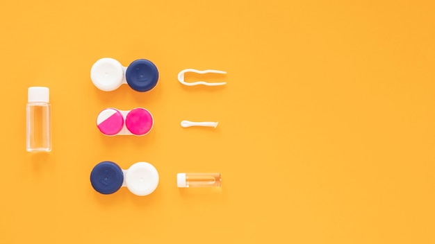 Eye care products on orange background with copy space