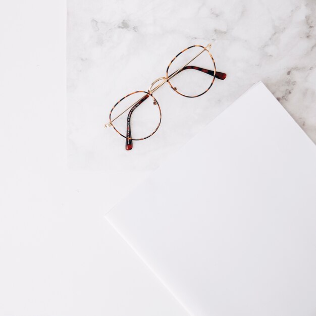 Eyeglasses and white paper on textured white backdrop