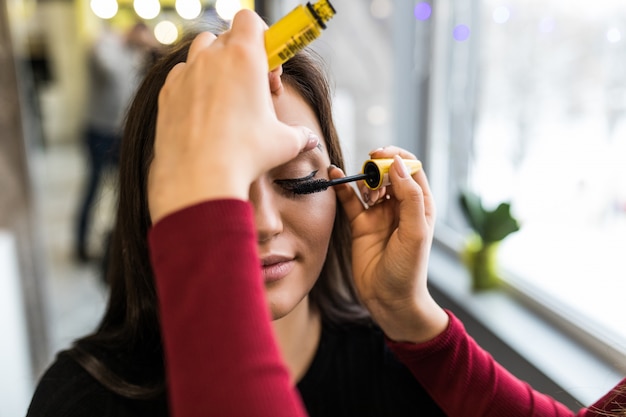 Eyelids make-up design for longhaired Pretty model in beauty salon