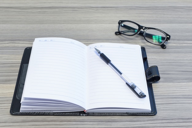 Eyewear, pen and opened diary on desk