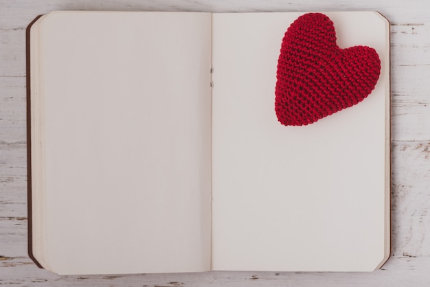 Free photo fabric heart on top of a blank notepad