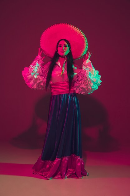 Free photo fabulous cinco de mayo female dancer on purple wall in neon light.