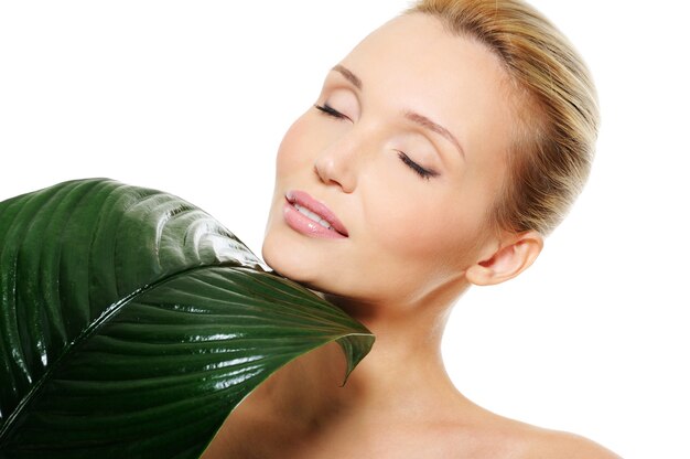 face of a beautiful cute  woman with large green leaf