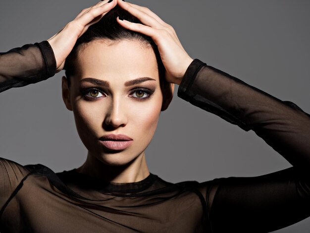 Face of a beautiful girl with smoky eyes makeup posing  over dark wall