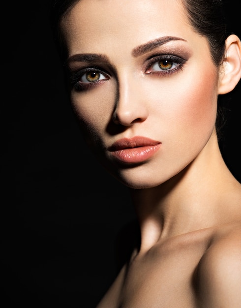 Free photo face of a beautiful girl with smoky eyes makeup posing at studio over dark background