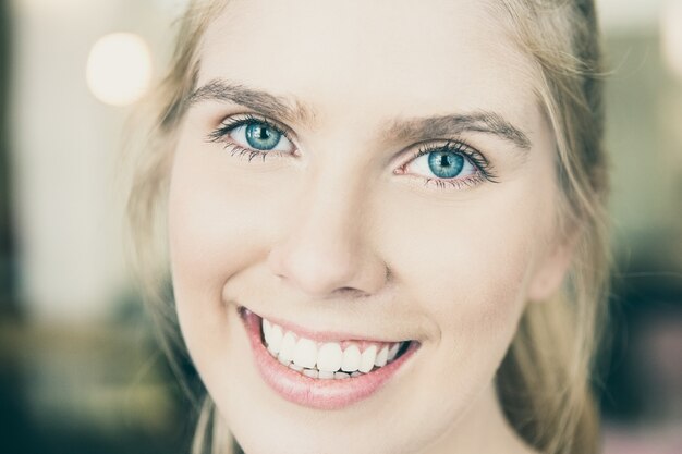 Лицо счастливой красивой молодой блондинки с голубыми глазами и белыми зубами