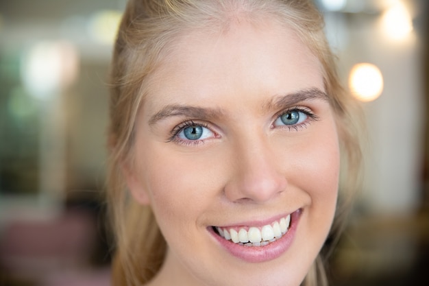青い目と白い歯を持つ幸せな美しい若いブロンドの女性の顔