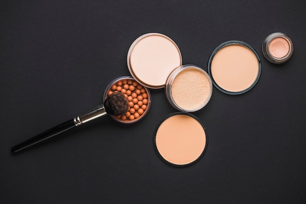 Face powder; bronzing pearls and makeup brush on black surface