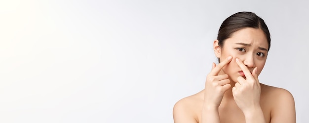 Problema della pelle del viso giovane donna infelice tocca la sua pelle concetto isolato per la cura della pelle asiatica