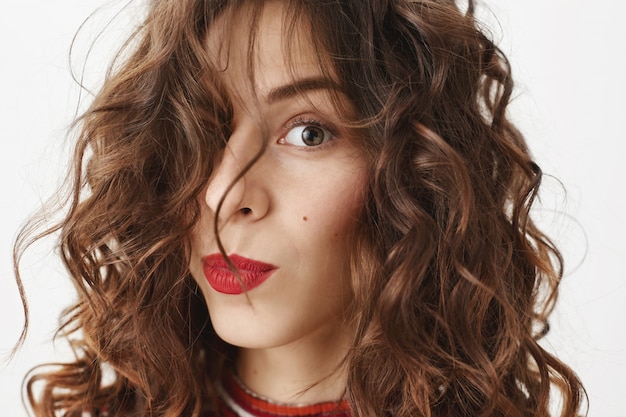 Face of stylish beautiful woman with red lipstick and curly haircut