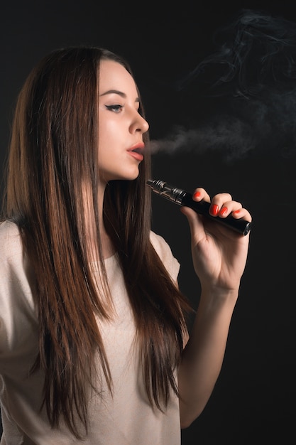 The face of vaping young woman at black studio