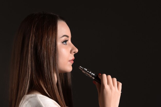 黒のスタジオでvaping若い女性の顔