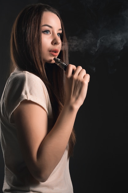 The face of vaping young woman at black studio