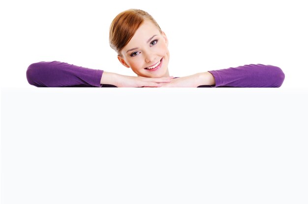 Face of the young beautiful smiling woman above the white blank banner