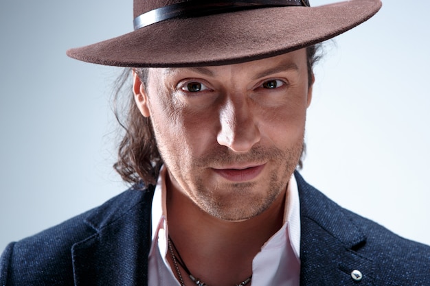 The face of young man portrait with hat on gray.