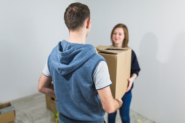 Faceless couple carrying box