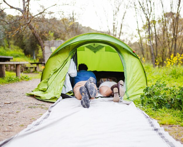 Faceless couple lying in tent